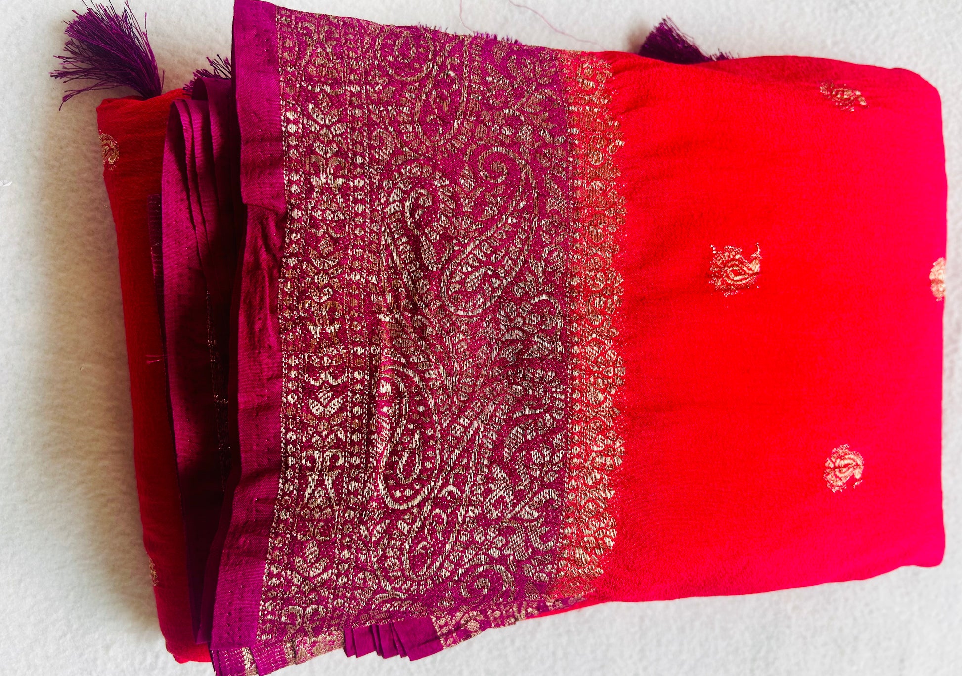 Pink fabric with gold paisley pattern on a white background